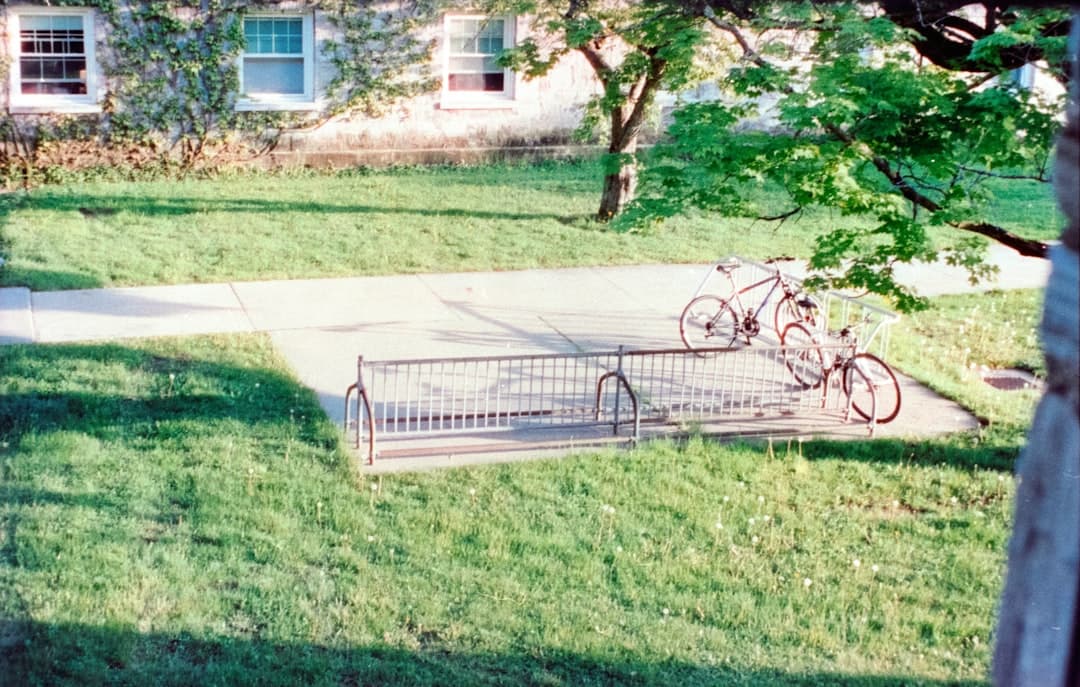 Two bicycles parked at a rack near building